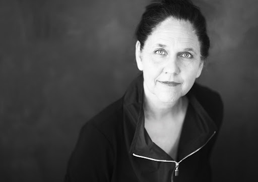 KI generiert: Das Bild zeigt eine Frau in einem Schwarz-Weiß-Porträt, die in die Kamera schaut. Der Hintergrund ist unscharf und der Fokus liegt auf ihrem Gesicht und Ausdruck.