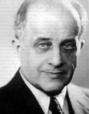 KI generiert: Das Bild zeigt eine schwarz-weiße Porträtaufnahme eines Mannes in einem Anzug. Der Mann schaut direkt in die Kamera.